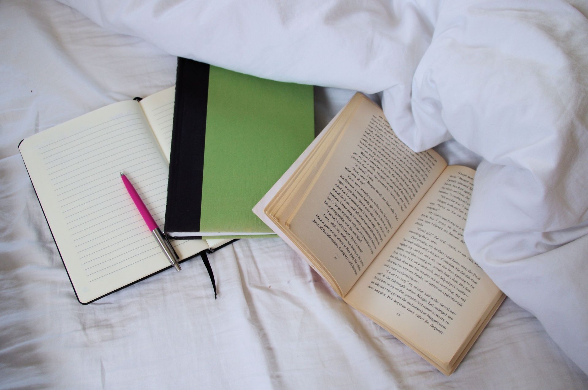 Student making notes beside an open textbook